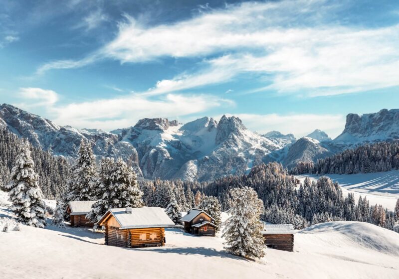 Houten huizen en een besneeuwde piste in de Italiaanse Alpen | Italië Uitgelicht |